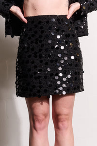 Model is wearing a black mini sequin skirt