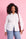 Model is wearing white long sleeve button up with denim jeans and a red bag 