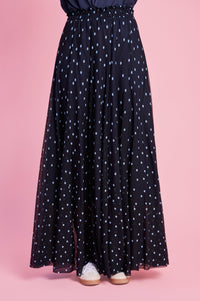 Model is wearing a blue spot mesh skirt with white sneakers 