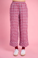 Model is wearing red gingham pants with burgundy socks 