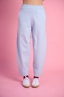 Model is wearing blue barrel leg sweat pants with white sneakers