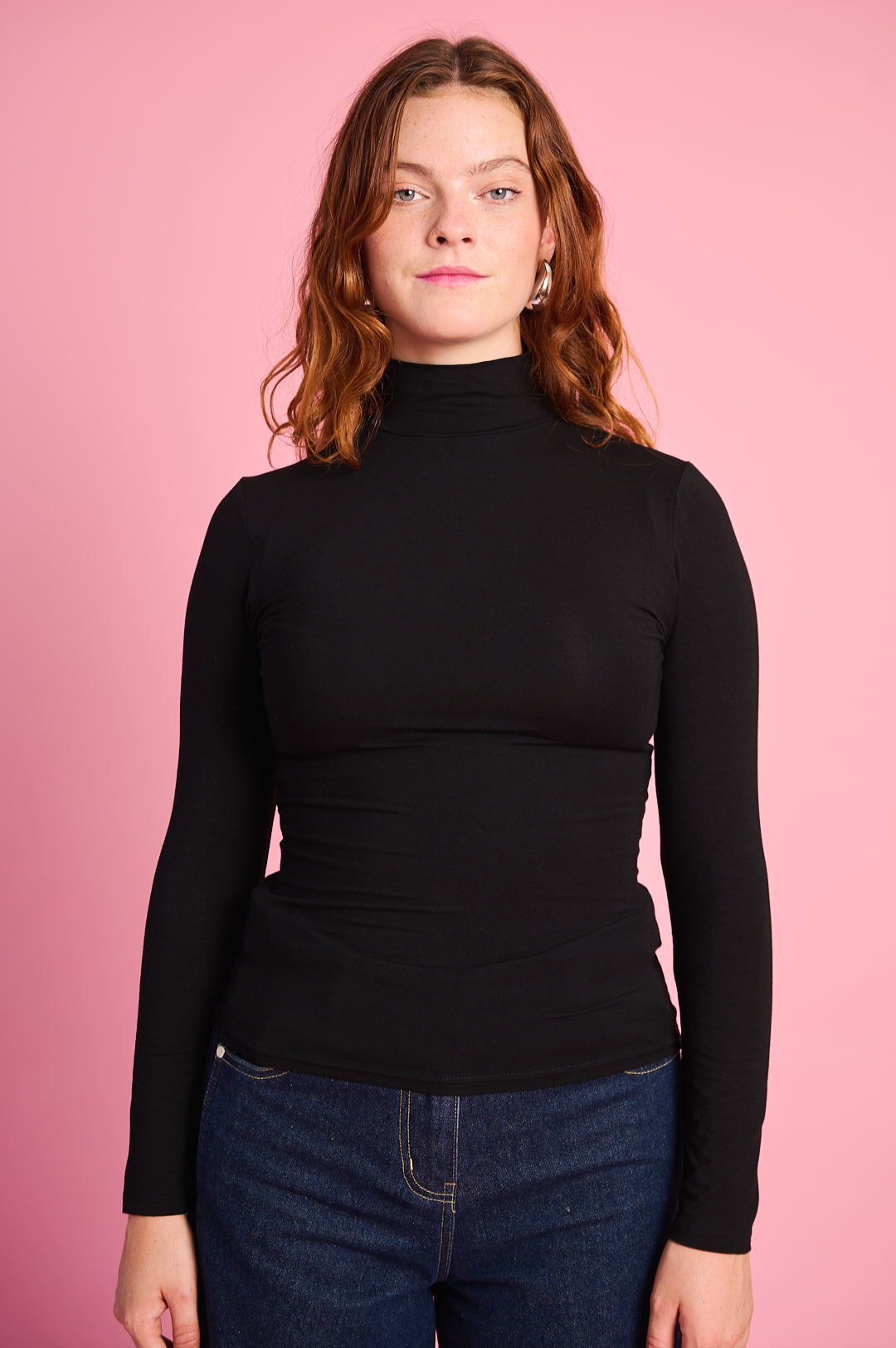 Model is wearing a black long sleeve polo with dark denim jeans 