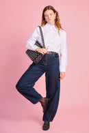 Model is wearing white peter pan collar with denim barrel jeans , a studded bag, belt and shoes