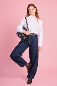 Model is wearing white peter pan collar with denim barrel jeans , a studded bag, belt and shoes