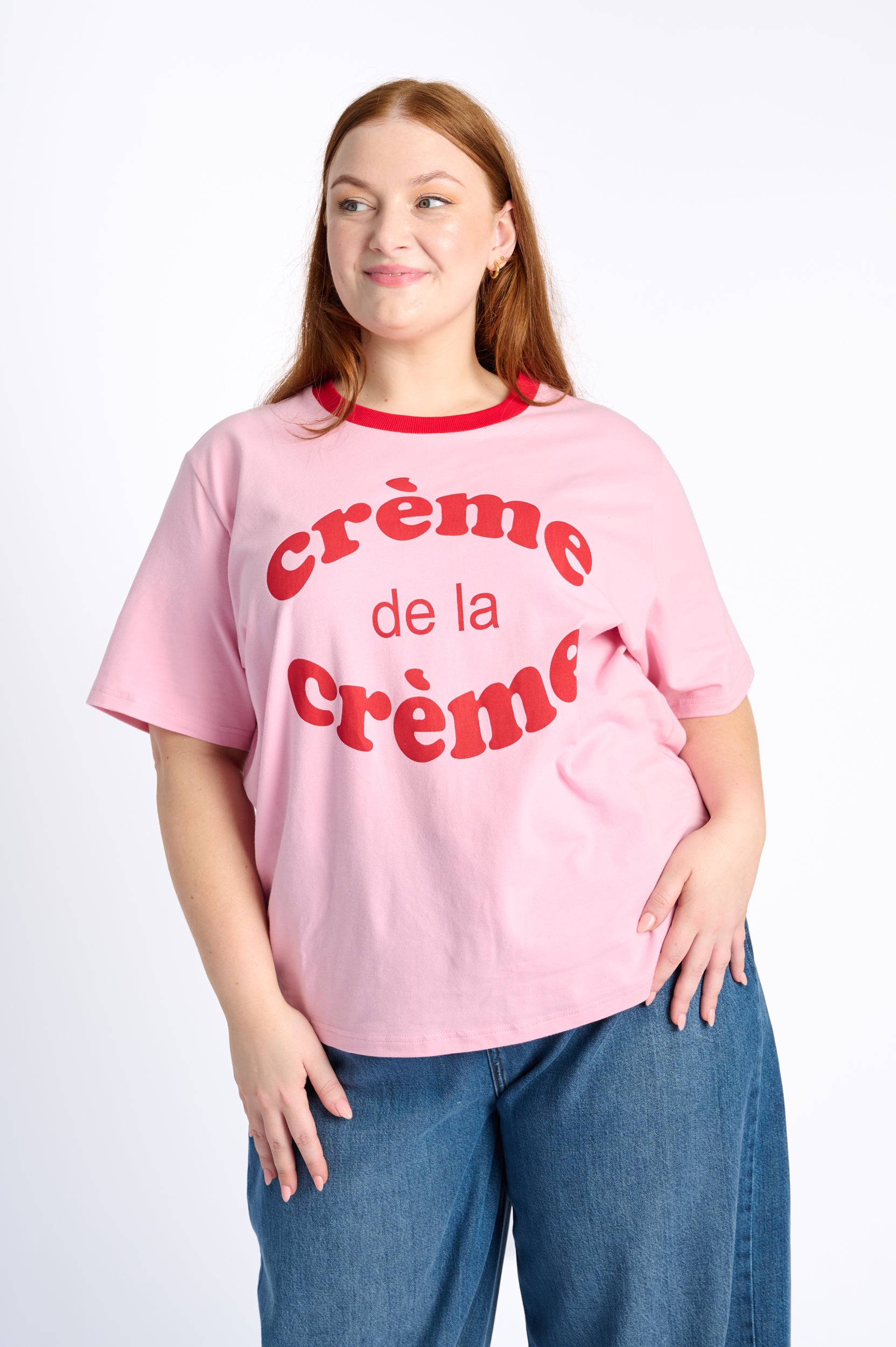 Person wearing a pink t-shirt with 'creème de la crème' text on a white background