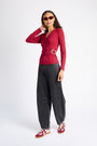 Model is wearing a long sleeve red top with black jeans and red and silver sneakers and red sunglasses