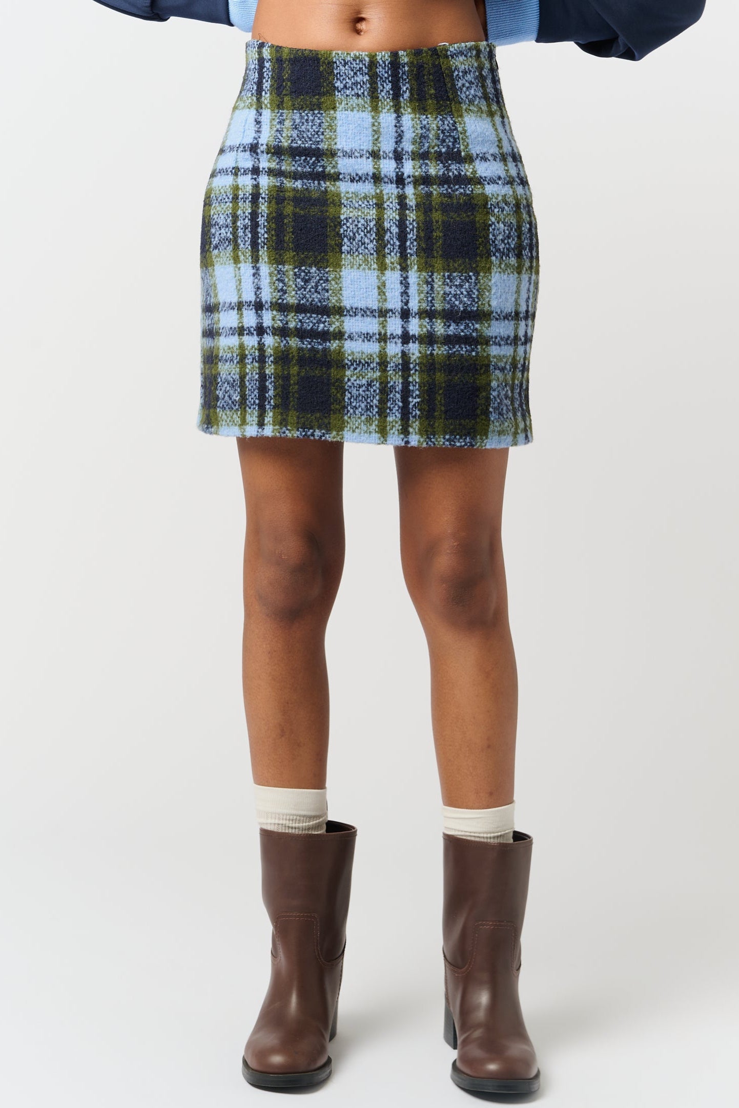 Model is wearing a green and blue melton check skirt with brown boots 