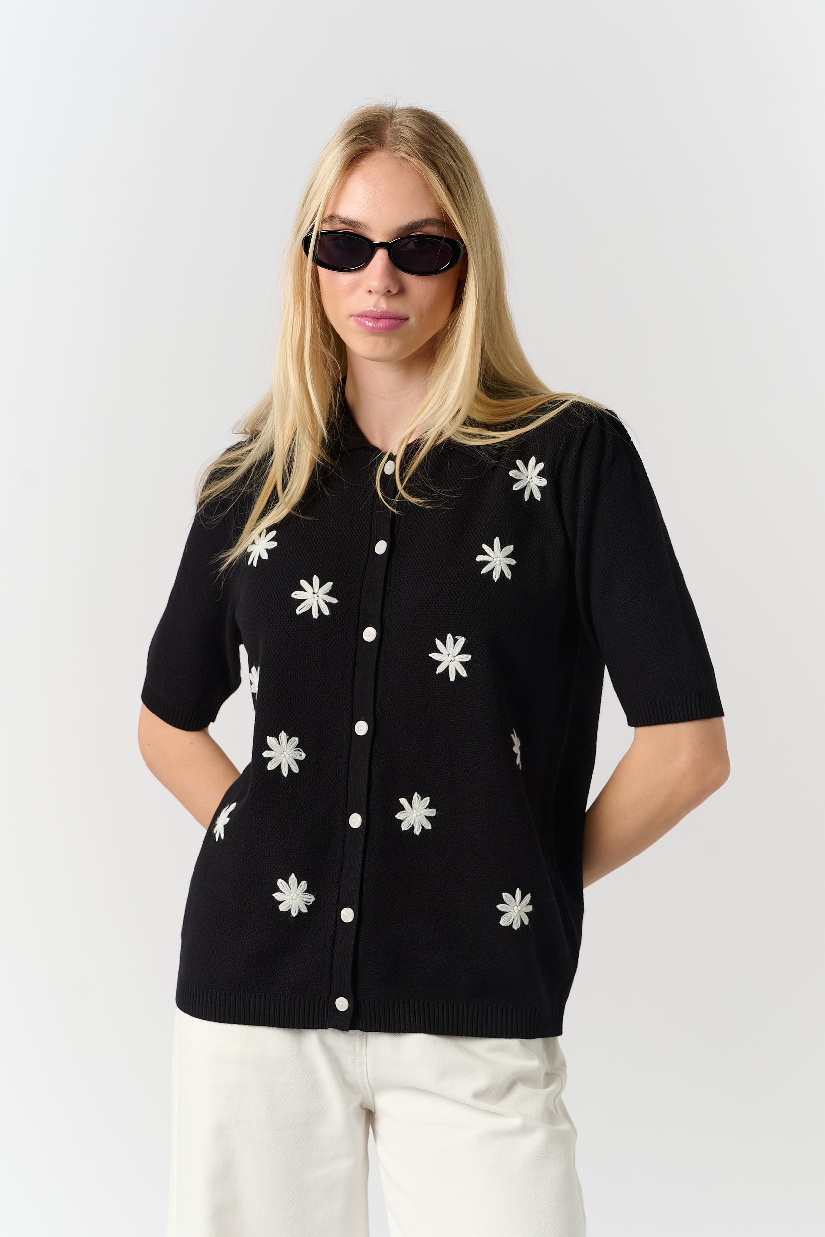 Model is wearing a black cardigan with daisy details 