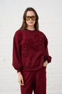 Model is wearing a burgundy sweat shirt jumper with floral detail Cornelli and matching sweatpants