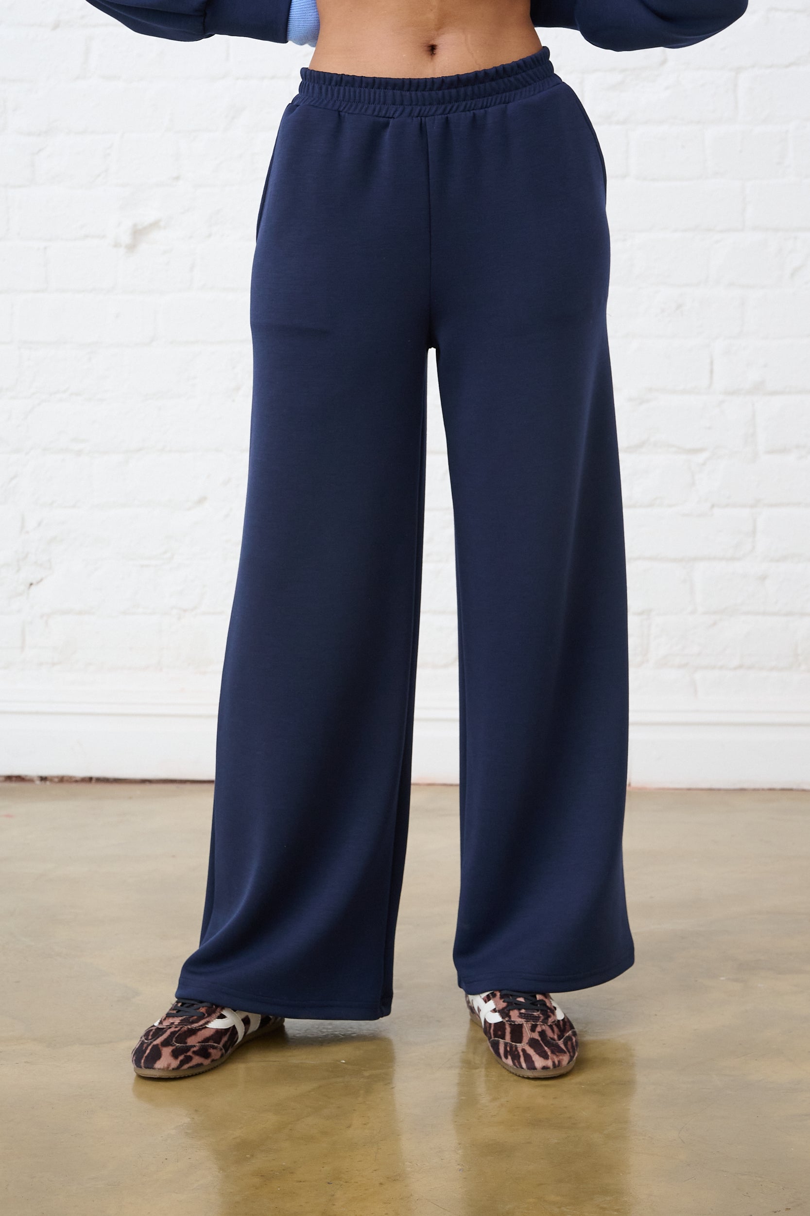Model is wearing navy wide leg sweat pants with leopard print shoes and a matching top