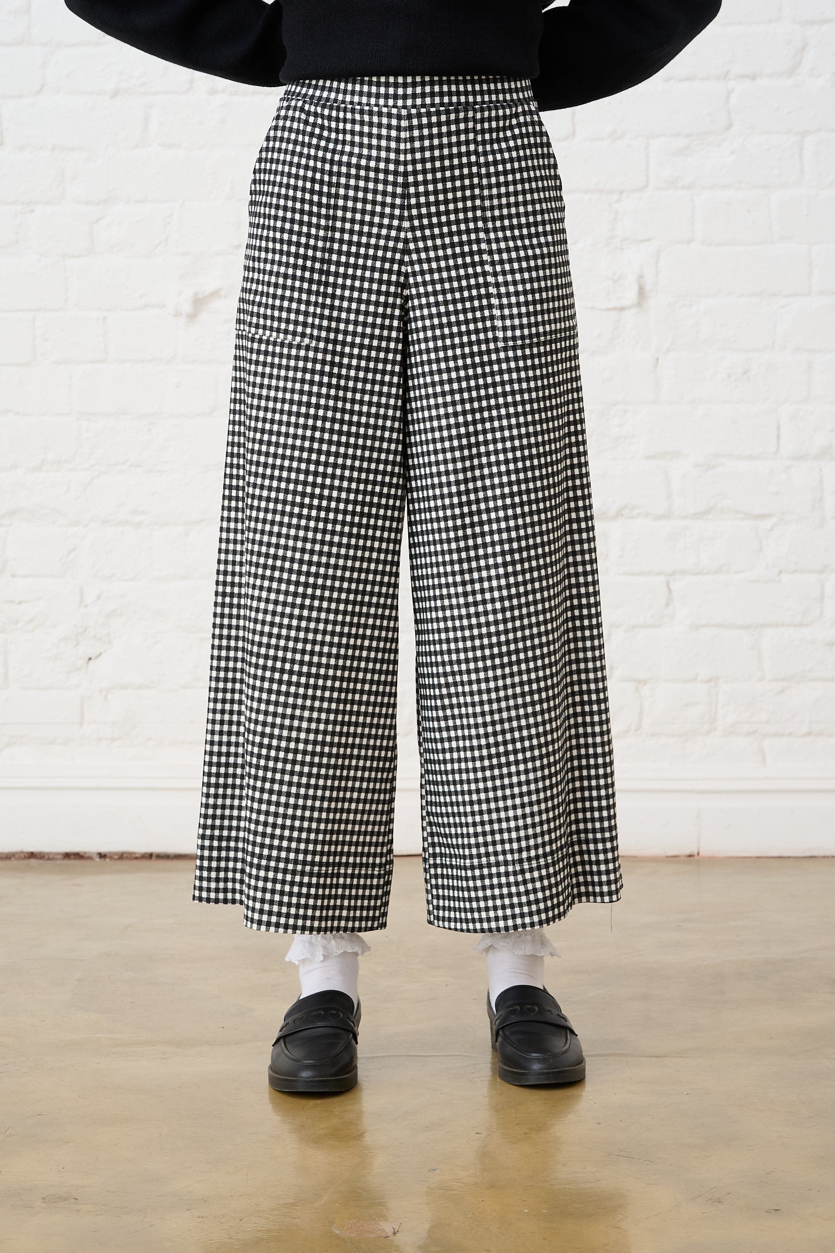 Model is wearing black and white check cropped pants with black shoes