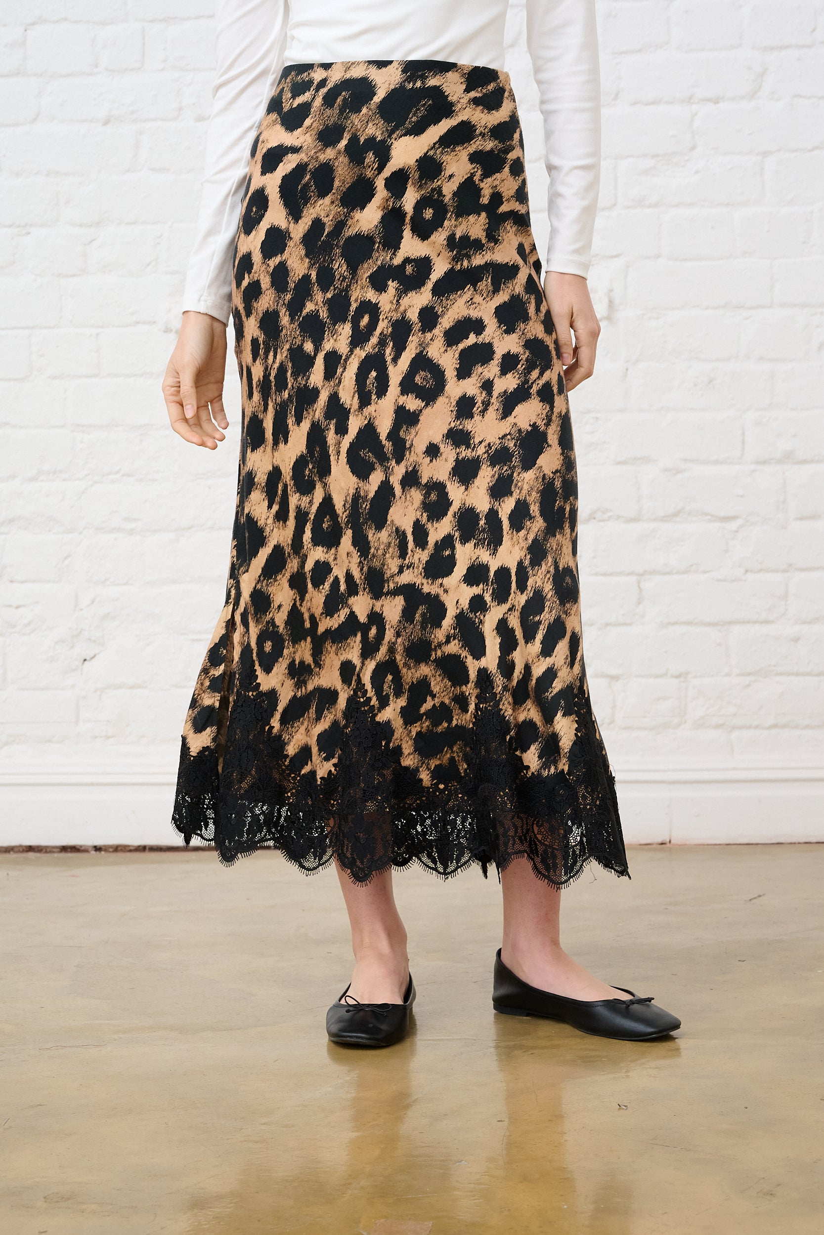 Model is wearing women's leopard print midi skirt with lace-trimmed hem and black pumps
