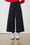 Model is wearing bengaline stretch cropped pants in black with white sneakers and a red jumper 