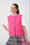 Model is wearing a pink gilet with a multi check skirt 