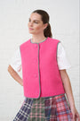 Model is wearing a pink gilet with a multi check skirt 