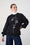 Model is wearing a black sweat shirt with white line art detail , with denim jeans and a white polo neck