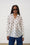 Model is wearing a white shirt with bee embroidery and dark wash jeans