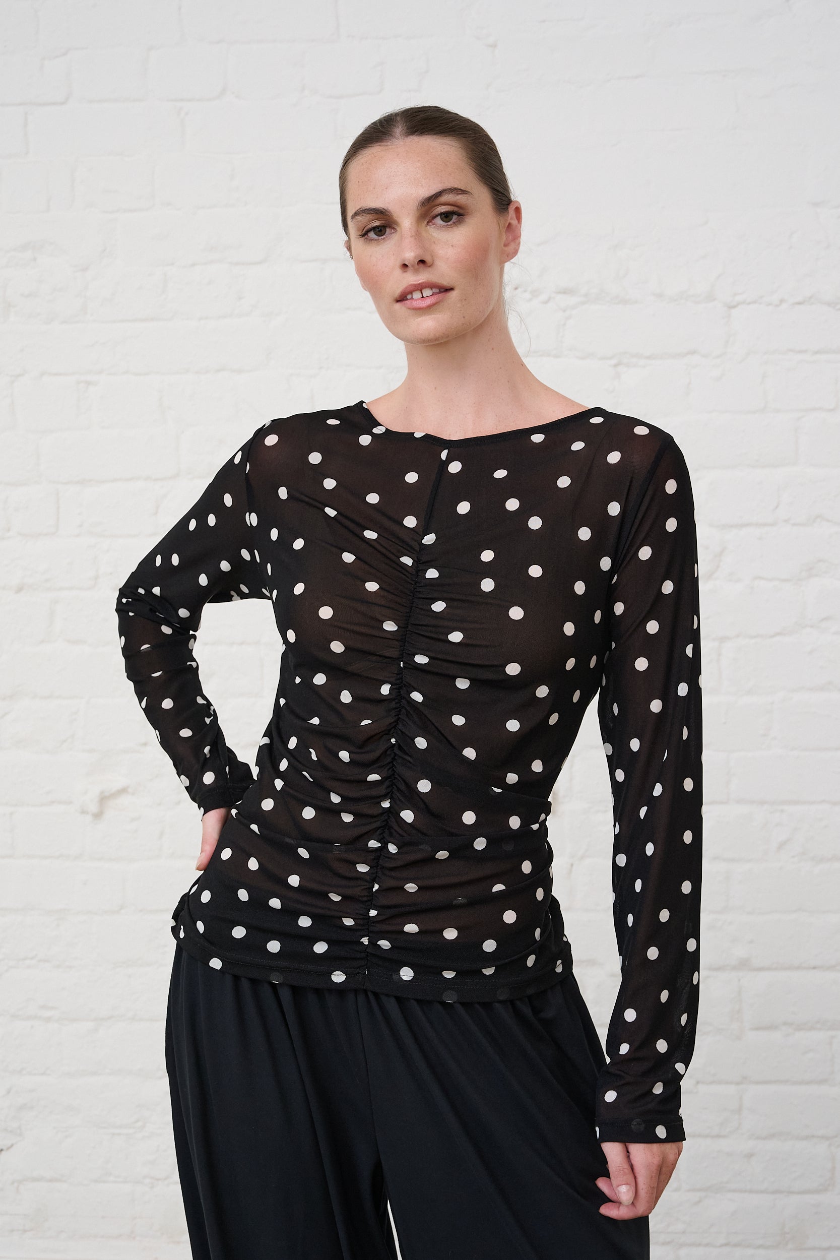 Model is wearing a black and white spot long sleeve top with black pants