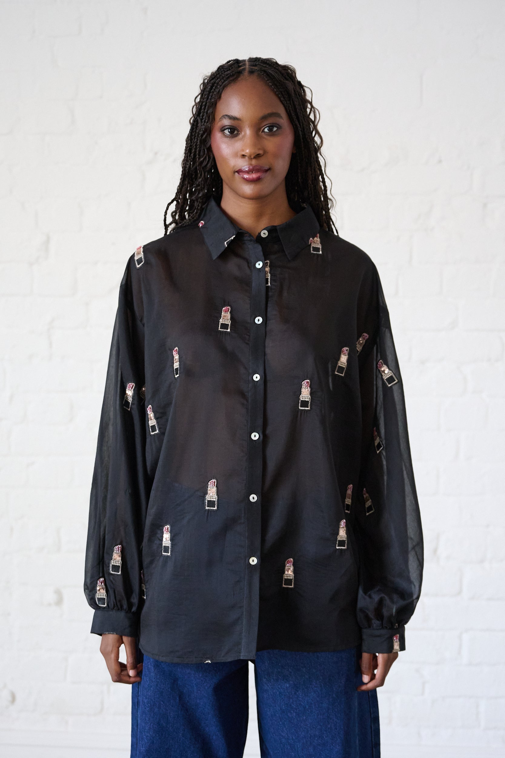 Model is wearing a bellow button down shirt that is slightly sheer with lipstick embroidery 