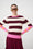 Model is wearing a burgundy, pink and orange bold striped jumper with burgundy mesh skirt 