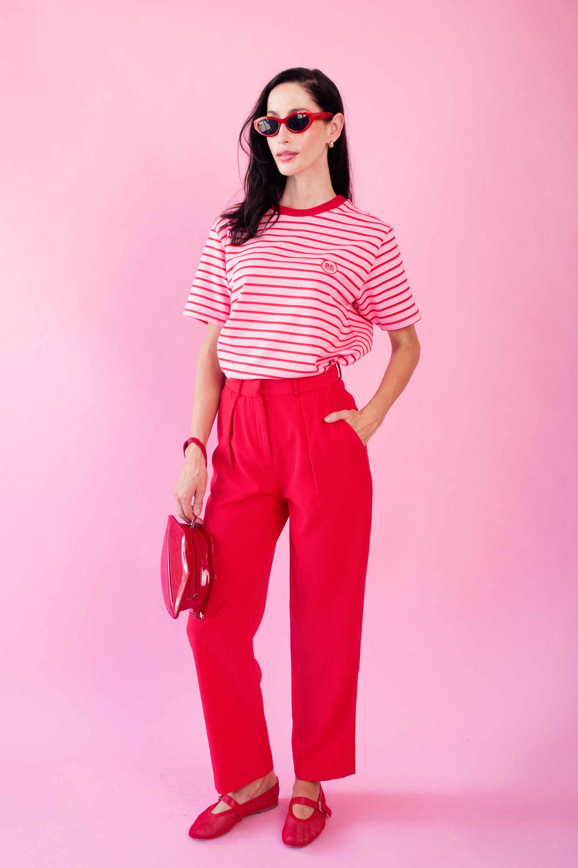 Model wearing red pants with pink and red striped Tee