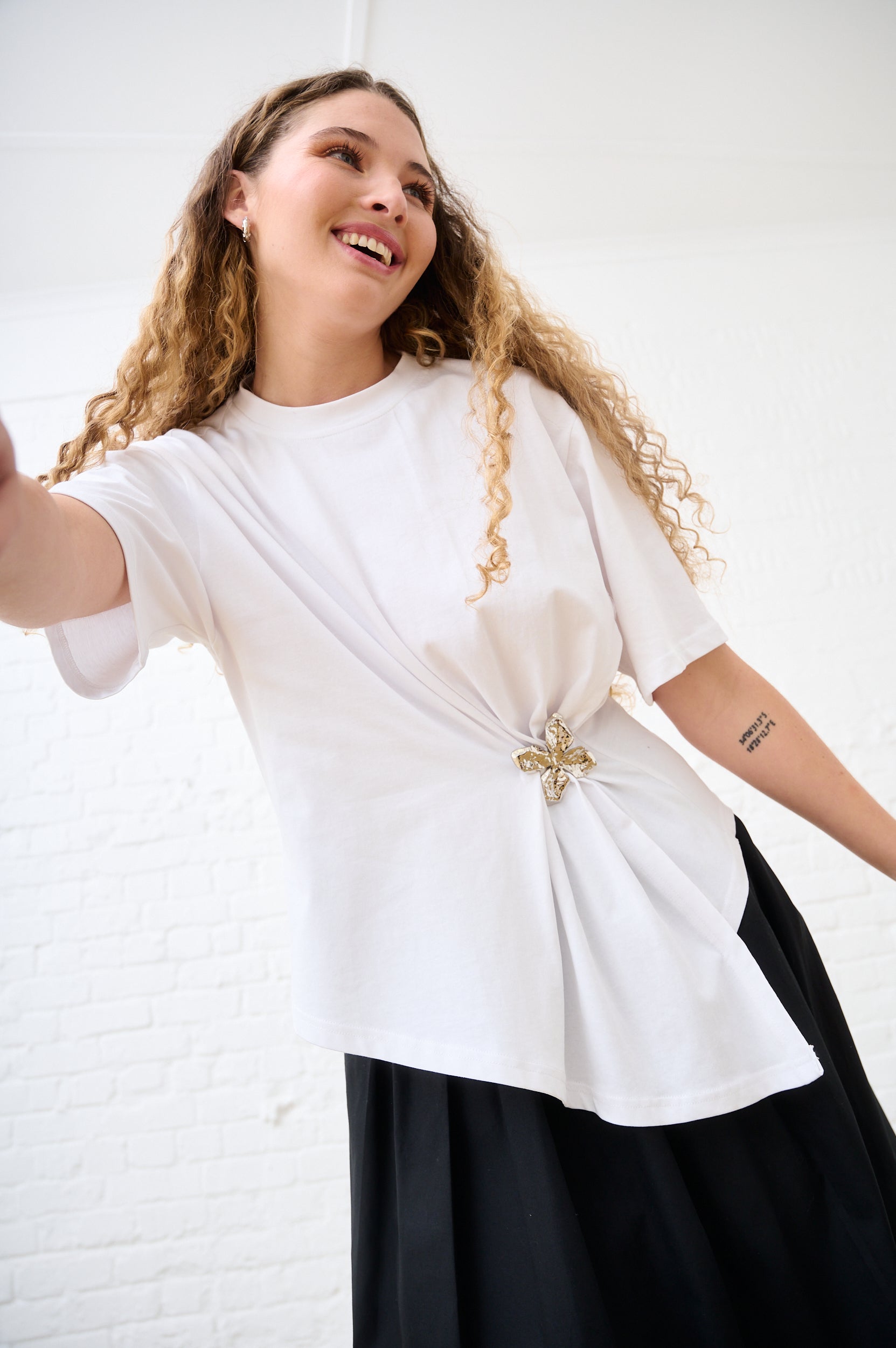 Model is wearing a white top with silver flower detail and a black skirt