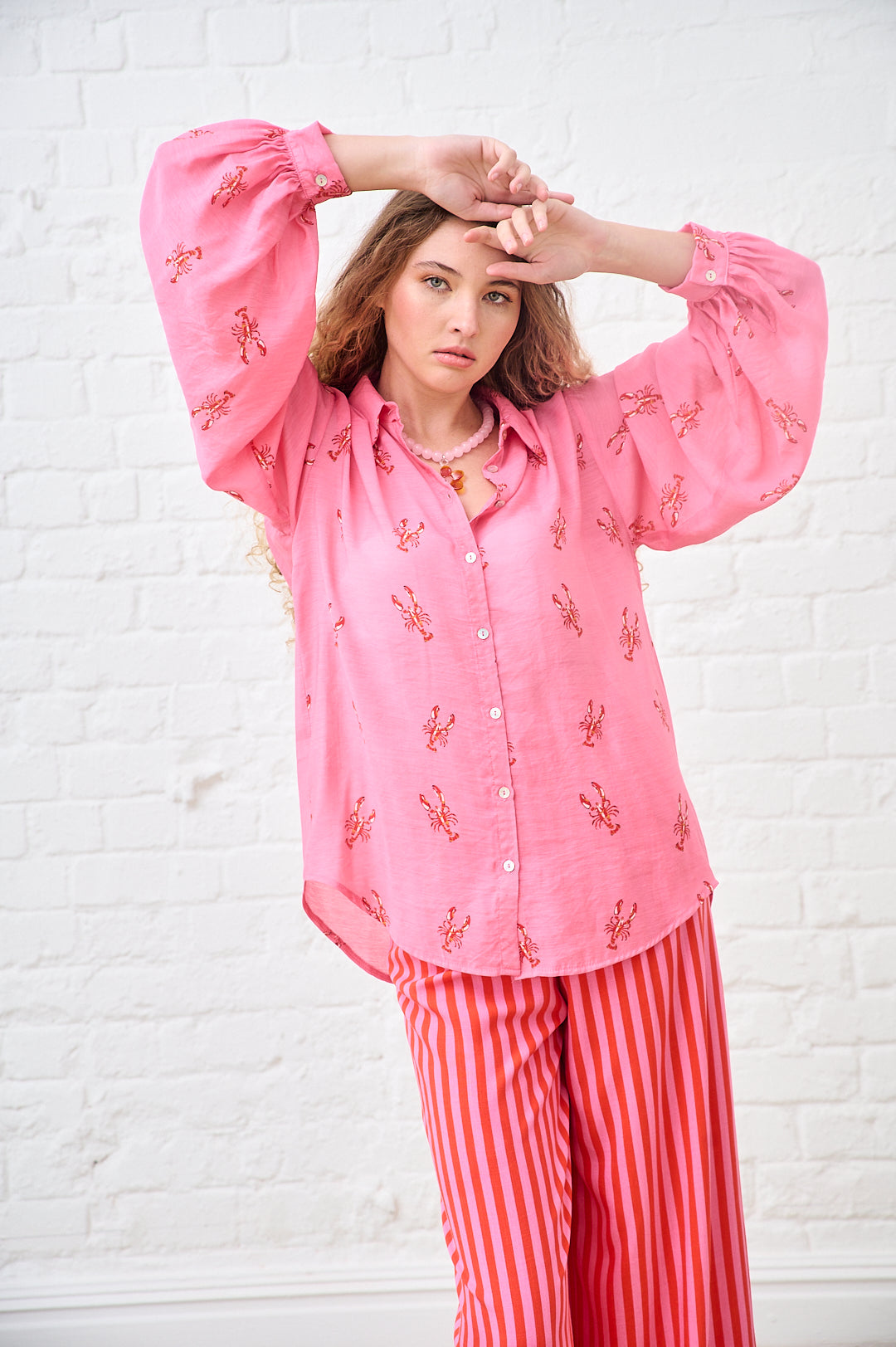 Model is wearing a pink and red bellow sleeve shirt, with prink and red striped pants