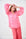 Model is wearing a pink and red bellow sleeve shirt, with prink and red striped pants