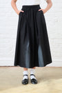 Model is wearing a black elasticated maxi skirt with white socks and black shoes