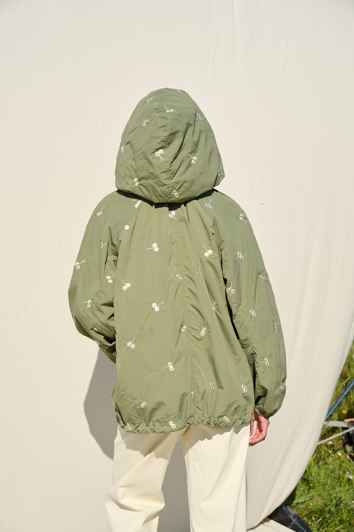 Model wearing fatigue green hooded jacket with daisy embroidery