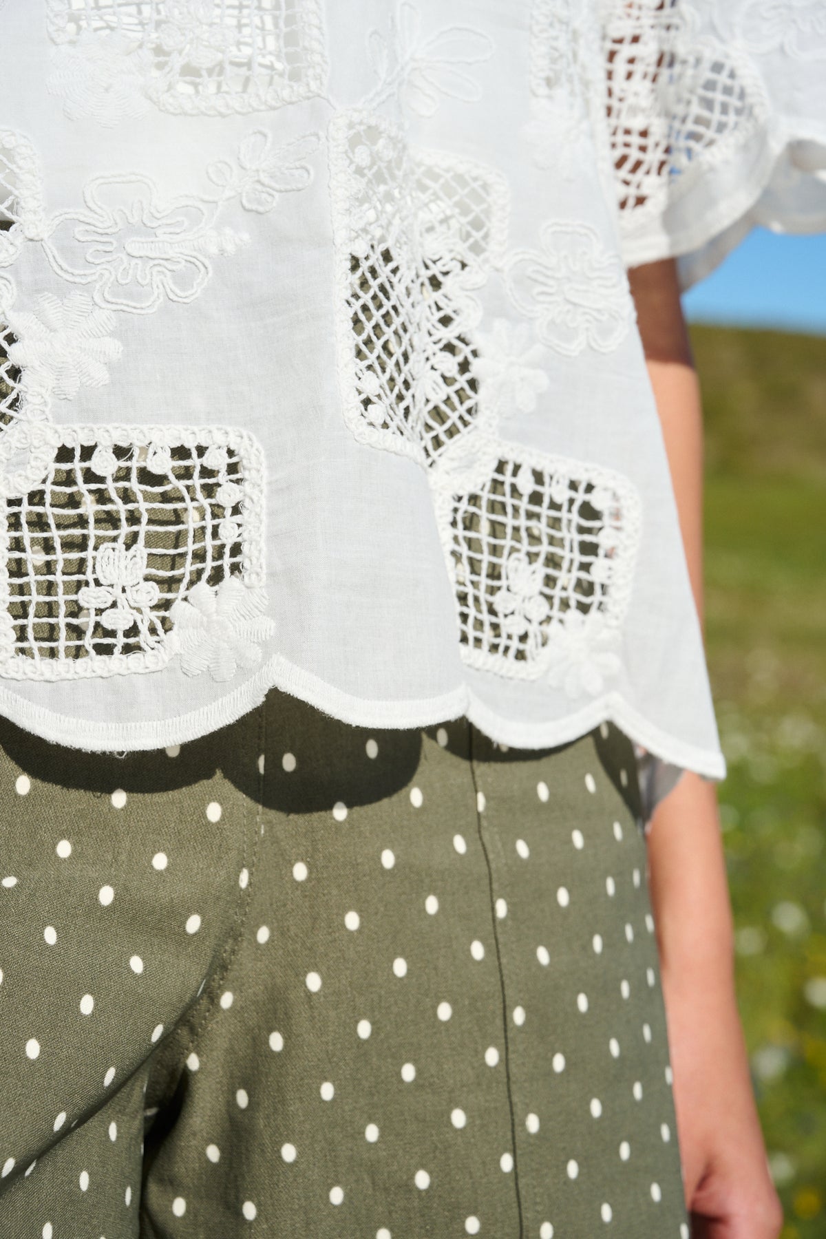 Model wearing milk white lace tee with scalloped sleeves and hem