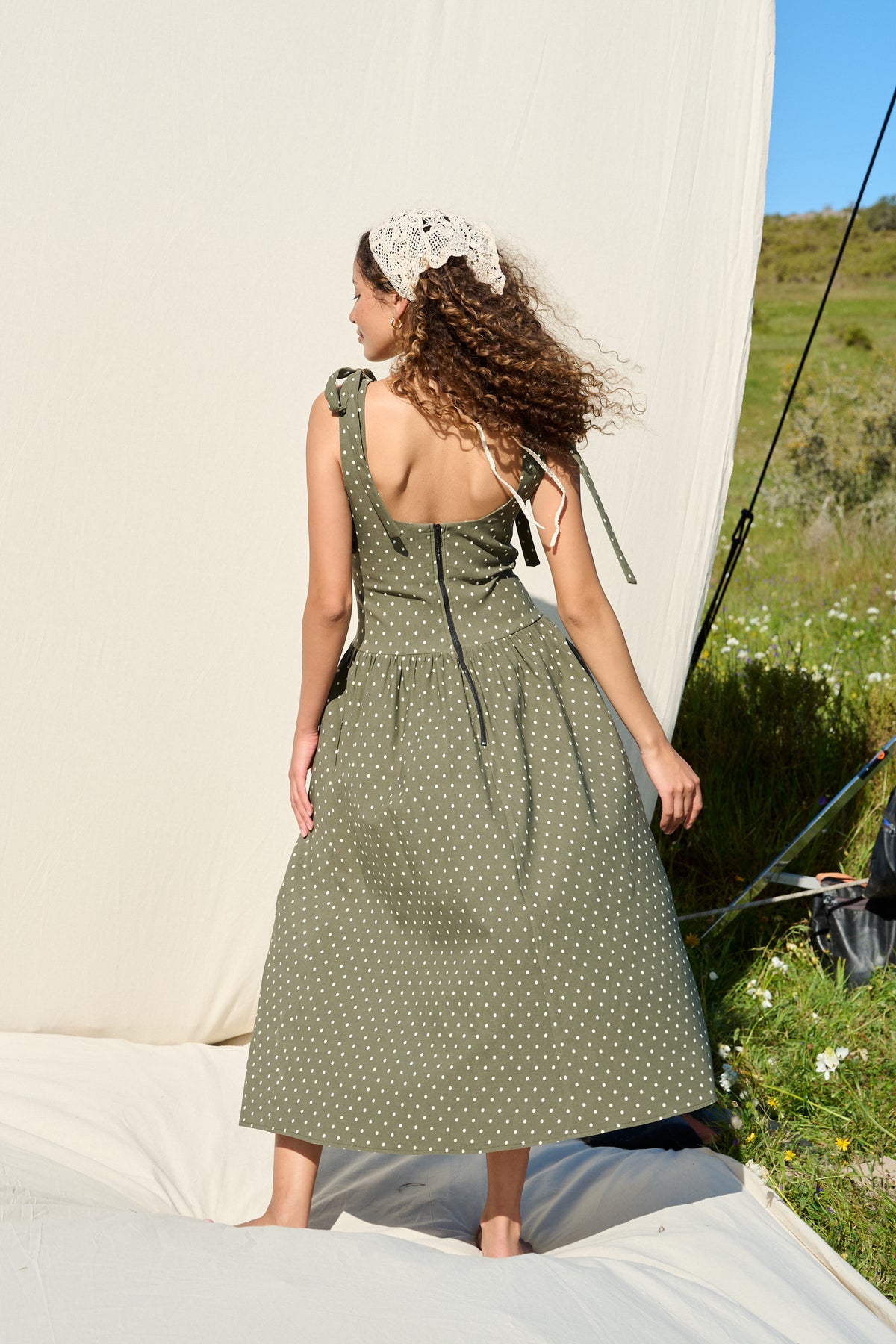 Model wearing fatigue green polka dot midi dress with tie straps