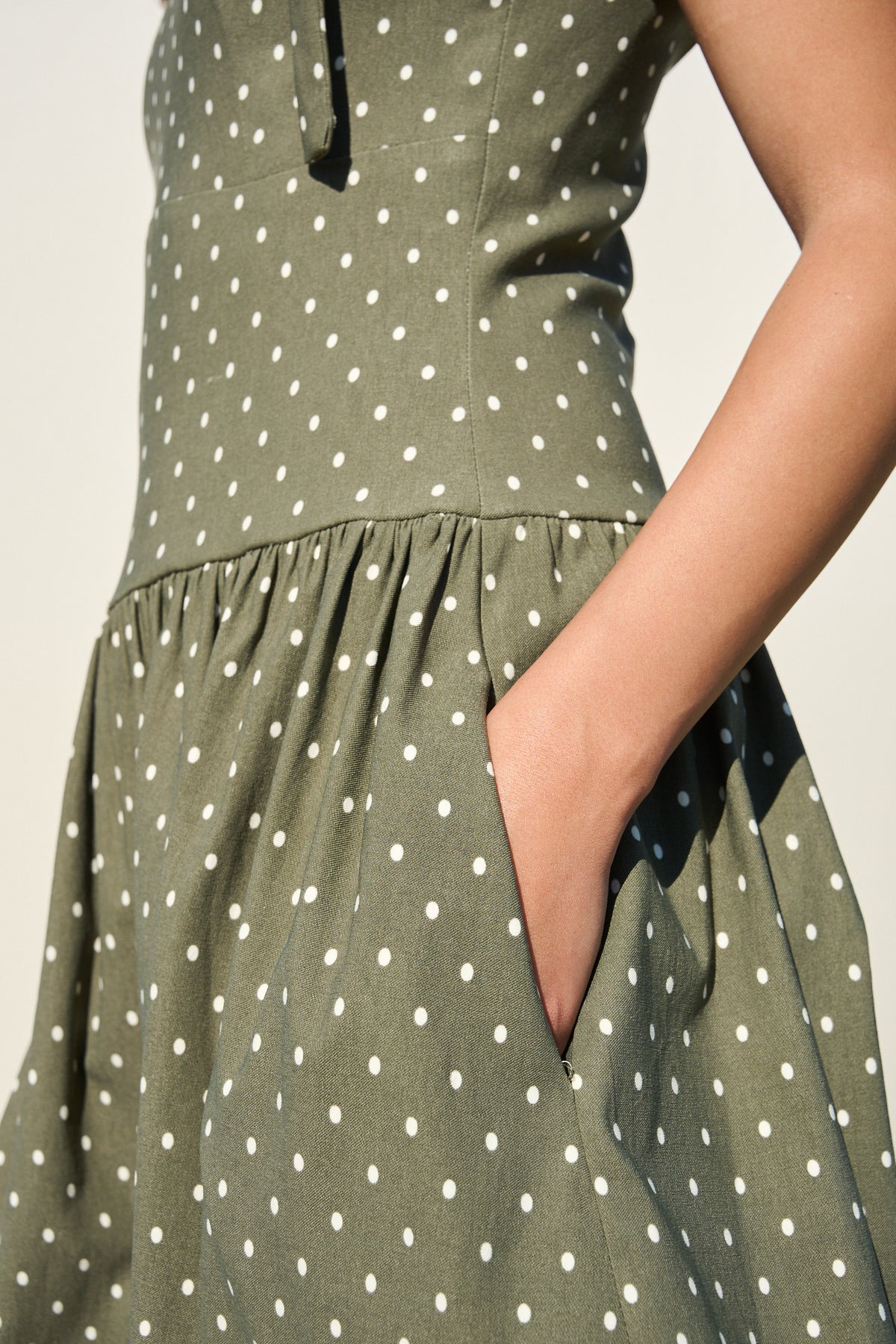 Model wearing fatigue green polka dot midi dress with tie straps