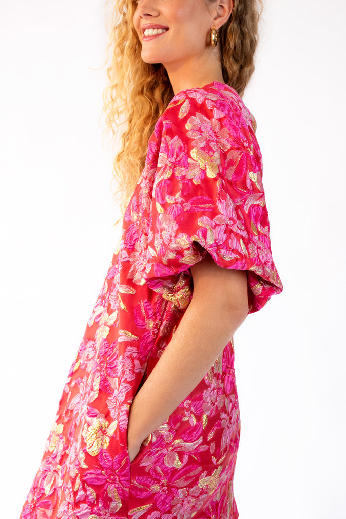 Model wearing pink, red and gold mini dress with puff sleeves