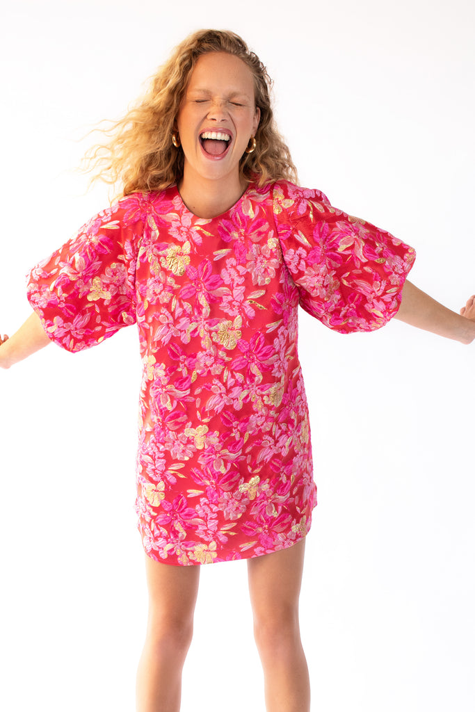 Model wearing pink, red and gold mini dress with puff sleeves