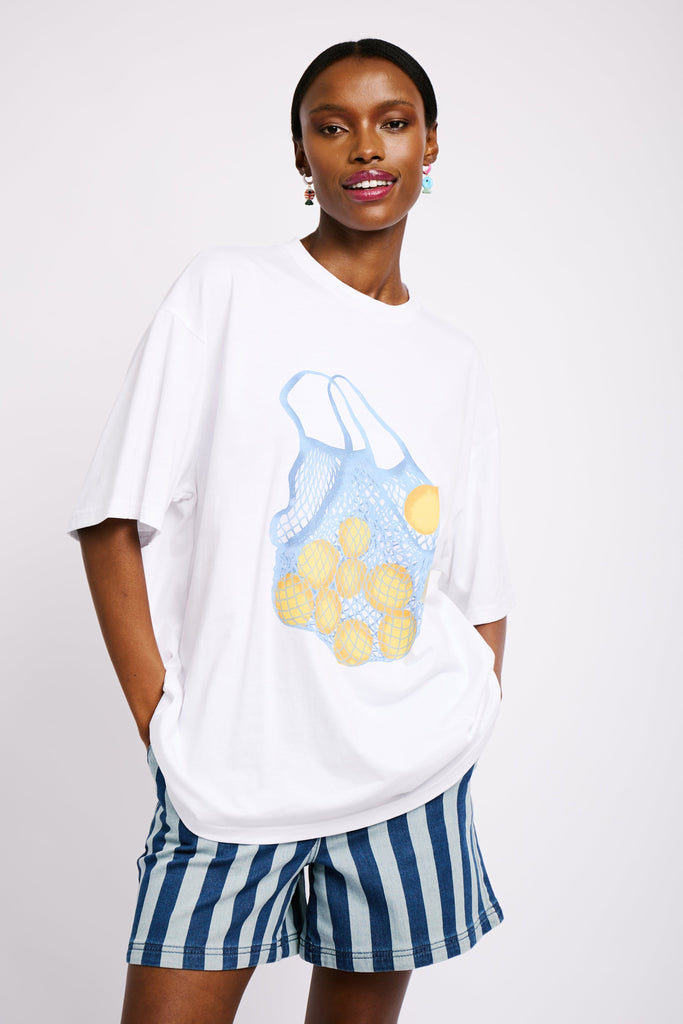 Model is wearing an oversized white T-shirt with a big statement print of a bag of yellow lemons