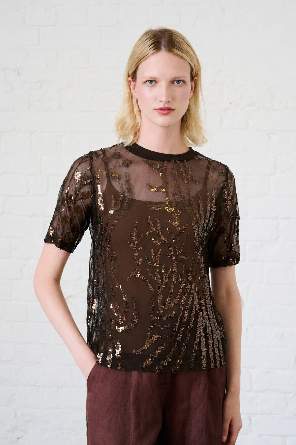 Model is wearing a sheer top with all over sequin detail 