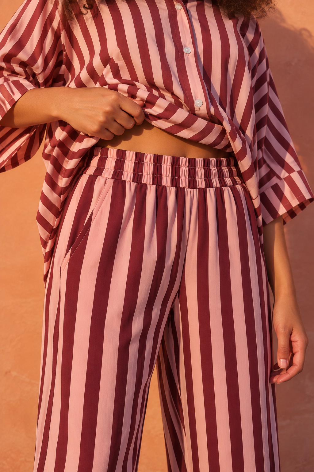 Model wearing burgundy and pink striped pants with horizontal stripe hems