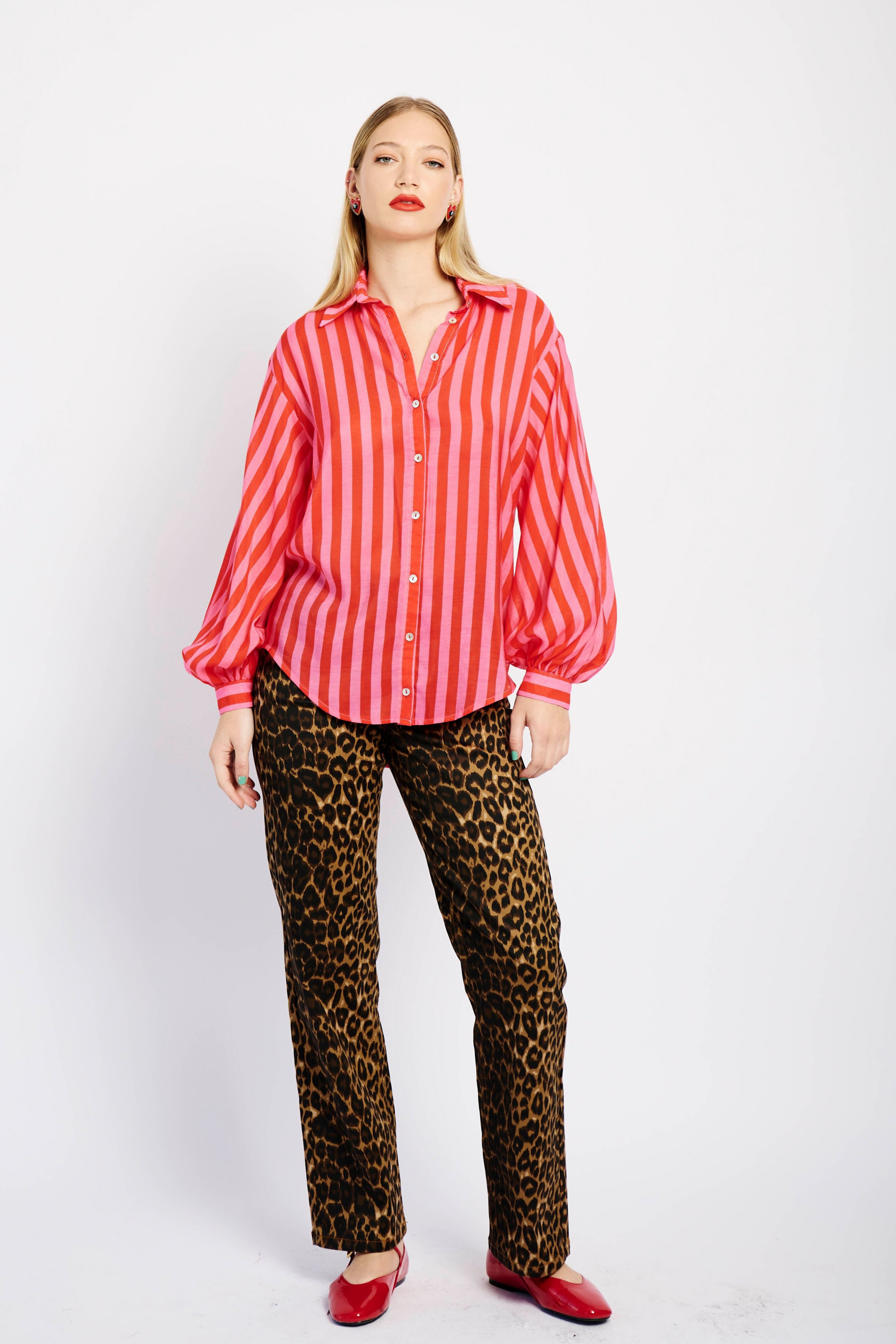 Model wearing pink and red striped shirt with animal print pants and red shoes
