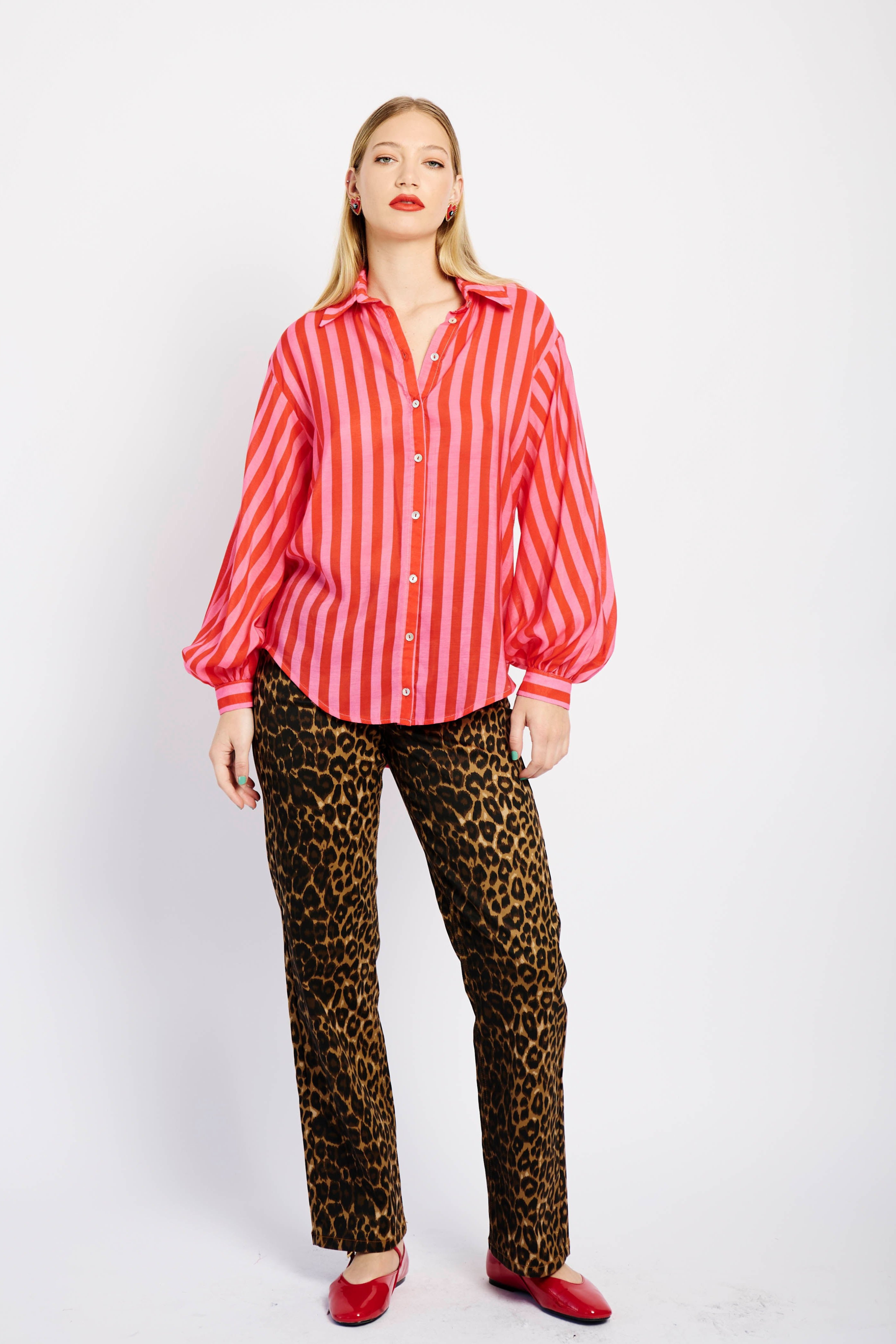 Model wearing pink and red striped shirt with animal print pants and red shoes