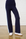Navy pants with a light blue stripe worn by a person against a white brick wall.