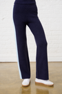 Navy pants with a light blue stripe worn by a person against a white brick wall.